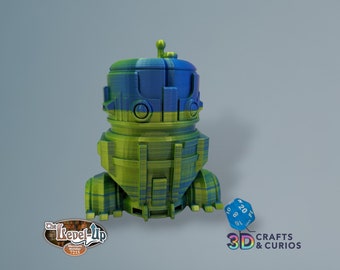 May include: A 3D printed robot figurine with a blue and green striped design. The robot has a round head with a small antenna on top. The robot is standing on a gray surface. The text "3D CRAFTS & CURIOS" is visible in the lower right corner of the image.