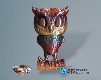 May include: A 3D printed owl figurine with a brown, gold, and black gradient finish. The owl is perched on a wooden branch with a blue and white dice beside it. The owl has large, round eyes and a detailed feather pattern. The text "The Level-Up" and "Merchant Number 7215" are visible on a label below the owl.