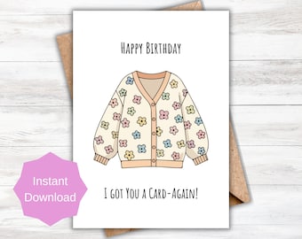 May include: A birthday greeting card with a cream-colored cardigan illustration adorned with colorful flower designs. The text "HAPPY BIRTHDAY" is at the top, and "I GOT YOU A CARD-AGAIN!" is at the bottom. The card is on a brown envelope.
