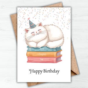 May include: A birthday card featuring a white cat wearing a party hat, sleeping on a stack of books. The books are blue, orange, and pink. The card reads "Happy Birthday" in black text.
