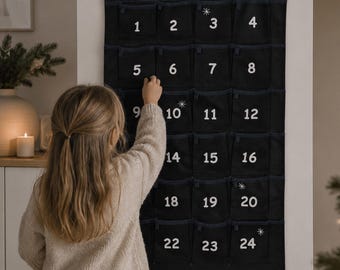 May include: A black fabric advent calendar with a triangular top, featuring the name Lena in white script, white numbered pockets from 1 to 24, and small white star accents. The wall-hanging organizer has a house-like shape with stitched details.
