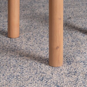May include: Two cylindrical light brown wooden furniture legs with a smooth finish and visible natural wood grain patterns. The legs are positioned vertically, showing a simple, sturdy design with flat circular bases at the bottom.