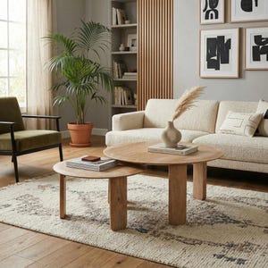 Puede incluir: Un salón con dos mesas de centro redondas de madera. Hay un sofá crema y un sillón verde. Una gran planta en maceta y obras de arte abstractas decoran la habitación. Una alfombra estampada cubre el suelo.