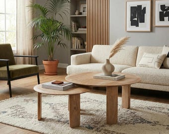 Puede incluir: Un salón con dos mesas de centro redondas de madera. Hay un sofá crema y un sillón verde. Una gran planta en maceta y obras de arte abstractas decoran la habitación. Una alfombra estampada cubre el suelo.
