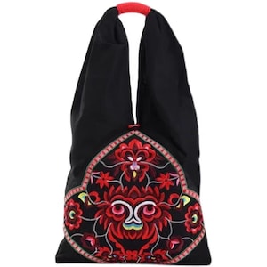 May include: Black tote bag with a red embroidered floral design. The bag has a red handle and a decorative embroidered panel in the center. The floral design includes red, pink, and yellow accents, creating a vibrant contrast against the black fabric.