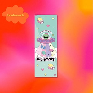 May include: A green alien in a flying saucer with the text "Just here for the books" and pink hearts and stars on a light blue background. This is a bookmark.