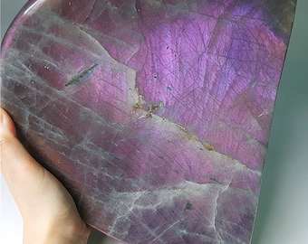 May include: A large, iridescent purple and gray labradorite dish. The dish is shaped like a half-circle and has a smooth, polished surface.