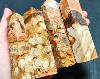 May include: Four brown, orange, and white agate crystal points with a swirling pattern. The points are arranged in a row, with the largest point on the right and the smallest point on the left.