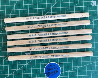 Puede incluir: Seis lápices de madera clara dispuestos horizontalmente, cada uno estampado con el texto No 919 CORGIE A PARIS FABRICATION FRANCAISE en tinta azul. Debajo de los lápices hay una pegatina azul circular con el texto Pencil Grocery.