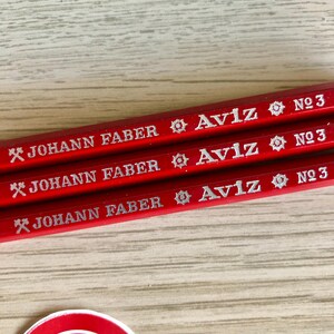 Może przedstawiać: Trzy czerwone oł&oacute;wki z srebrnym napisem. Oł&oacute;wki są oznaczone "JOHANN FABER Aviz N№ 3".