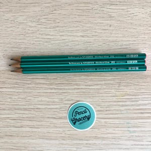 May include: Three green pencils with the text "Schwan & STABILO Othello 282 GERMANY" and lead grades HB=2 1/2, H=3 1/2, and B=2. A round sticker with the text "Pencil Grocery" is also visible.