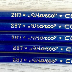 Puede incluir: Primer plano de cinco l&aacute;pices azules con letras doradas. Cada l&aacute;piz tiene el n&uacute;mero "287" y el texto "&laquo;Viarco&raquo; * CO" impreso en &eacute;l.