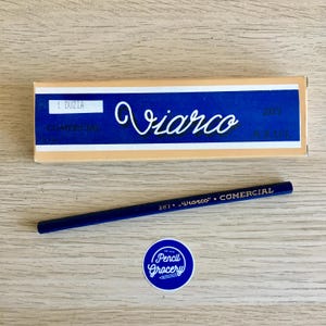 Puede incluir: Una caja de l&aacute;pices azules Viarco etiquetados como "Comercial" con un solo l&aacute;piz azul sobre una superficie de madera. El l&aacute;piz est&aacute; etiquetado como "287 Viarco Comercial".