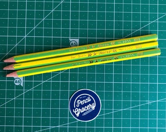Puede incluir: Tres lápices amarillos y verdes con letras doradas que dicen "Best Quality Horse No. 2200 HB". Los lápices están sobre una estera de corte verde con una pegatina azul y blanca que dice "Pencil Grocery".