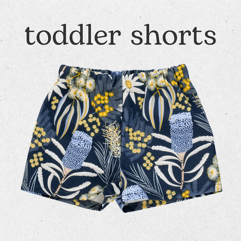 May include: Toddler shorts with a blue and white floral print featuring yellow flowers and leaves.