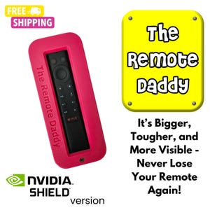 May include: A pink silicone remote control holder with the text "The Remote Daddy" printed on the side. The holder is designed to fit a black remote control with buttons and a Netflix logo. The text "NVIDIA SHIELD version" is printed below the holder.