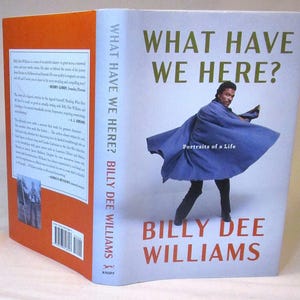 May include: A book cover with the title "WHAT HAVE WE HERE?" and the author's name, BILLY DEE WILLIAMS, in red. The cover features a photo of a person in a blue coat. The book is titled "Portraits of a Life".