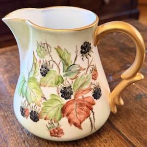 May include: A set of three ceramic mugs with a speckled, matte finish. Each mug features a different color: light blue, cream, and gray. The mugs have a simple, modern design and a comfortable handle.