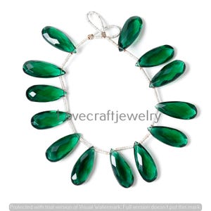 May include: A strand of faceted, teardrop-shaped green gemstones. The gems are strung on a silver-colored wire, with a loop at the top. The image includes the text "lovecraftjewelry".