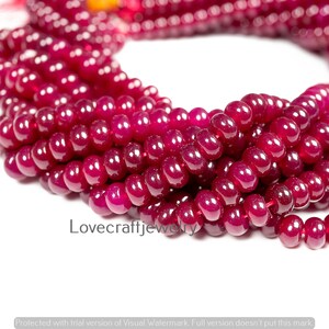 Op de afbeelding: Close-up van een streng dieprode, gepolijste edelsteen kralen. De kralen zijn rond en gelijkmatig van grootte, geregen om een ketting of armband te vormen. De tekst "Lovecraftjewelry" is zichtbaar op de afbeelding.