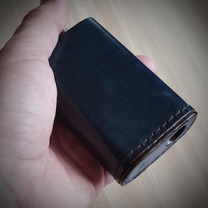 May include: A dark blue leather case with brown stitching. The case is rectangular in shape and has a smooth surface.