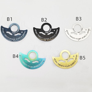 May include: Five different watch movement parts, each with a different color and finish. The parts are all shaped like a crescent moon and have the text "4R36A TWENTY-FOUR JEWELS JAPAN" printed on them.