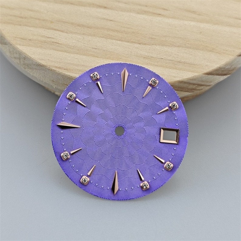 K&ouml;nnte beinhalten: Ein violettes Zifferblatt mit ros&eacute;goldenen Akzenten und Diamant-Stundenmarkierungen.
