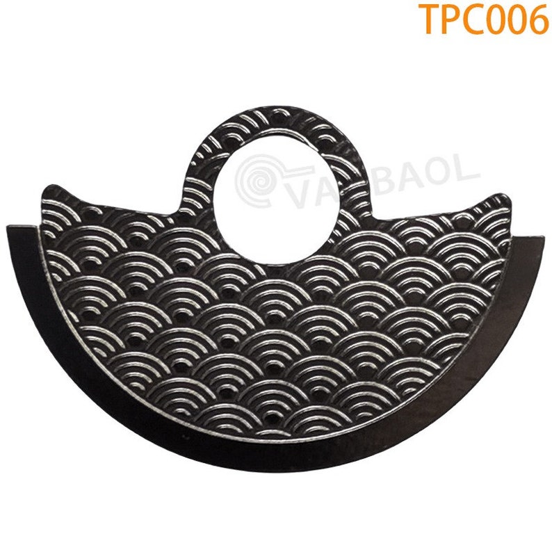 May include: A black metal watch part with a circular hole and a pattern of overlapping semicircles. The part is labeled "TPC006".