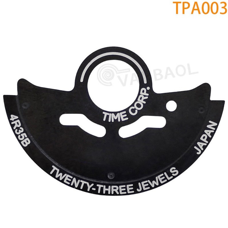 May include: Black metal watch movement part with white text that reads "TIME CORP. TWENTY-THREE JEWELS JAPAN 4R35B".