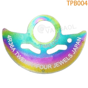 May include: A rainbow iridescent metal watch movement part with the text "4R36A TWENTY FOUR JEWELS JAPAN TIME CORP." printed on it.