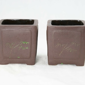 May include: Two brown square ceramic bonsai pots with green bamboo designs.