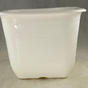 May include: White plastic planter with a ribbed texture and a decorative floral design. The planter is square shaped and has a wide opening.