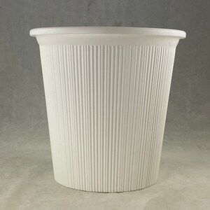 May include: A white plastic planter with a ribbed texture. The planter is cylindrical and has a wide opening.