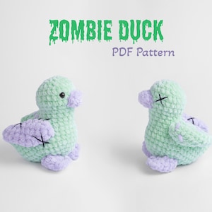 Puede incluir: Un juguete de peluche de pato zombie de crochet verde y morado. El pato tiene ojos cosidos y una boca cosida con una 'X' encima. El juguete está sentado sobre una superficie blanca. El texto 'ZOMBIE DUCK PDF Pattern' está escrito encima del juguete.