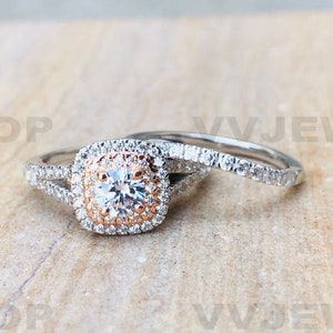 May include: A two-piece wedding ring set with a square halo engagement ring featuring a center stone surrounded by smaller diamonds. The engagement ring is set in rose gold and the wedding band is set in white gold.