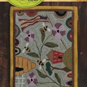 May include: A punchneedle embroidery piece titled "708 - Bee Grateful." The design features bees, flowers, a beehive, and an American flag. The piece measures 6 x 9 inches and is framed with a yellow border. The Threads that Bind logo is at the top.