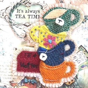 Puede incluir: Una pieza de arte textil caprichosa con tazas de té coloridas apiladas con bolsitas de té. El texto "It's always TEA TIME" se muestra encima de las tazas. Las tazas son de color verde, amarillo, azul, naranja y rojo.