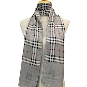May include: A gray silk scarf with a plaid pattern and white polka dots. The scarf has a gray and white logo on each end.