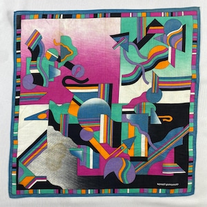 Könnte beinhalten: Quadratisches Tuch mit einem abstrakten, geometrischen Design. Es zeigt eine Mischung aus leuchtenden Farben wie Lila, Türkis, Orange und Schwarz. Das Design umfasst Formen und Linien, mit einem blauen Rand und dem Text "kansai yamamoto" in der unteren rechten Ecke.
