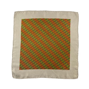 May include: A square scarf featuring a central panel with a repeating pattern of overlapping orange, yellow, and olive green crescent shapes. The scarf has a wide, solid beige border and includes the text HERMES-PARIS printed in the bottom corner.