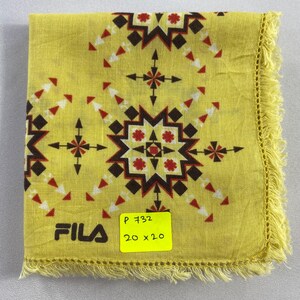 May include: Yellow FILA handkerchief with a geometric pattern in red, brown, and white. The handkerchief has a fringed edge and the FILA logo in black. A yellow sticker indicates the size is 20 x 20 inches.