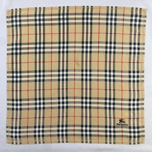 May include: Tan, black, white, and red plaid handkerchief with the Burberrys logo in the bottom right corner. The handkerchief has a classic plaid pattern with intersecting lines of varying widths and colors. The overall design is symmetrical.