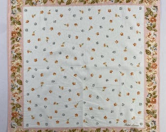 May include: A white cotton handkerchief with a pink border and a floral pattern. The border features a repeating pattern of small flowers and leaves. The center of the handkerchief has a smaller floral pattern with a repeating pattern of small flowers. The handkerchief has the text "Ralph Lauren" in the bottom right corner.