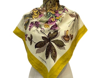 May include: Square silk scarf with a cream background and a botanical print featuring leaves and flowers in shades of brown, purple, and yellow. The scarf has a bright yellow border and the brand name "LANCEL PARIS" is visible.