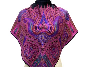 May include: A black silk scarf with a paisley pattern in shades of pink, purple, and gold. The scarf has a fringed edge and the brand name "LANCEL" is visible in the lower right corner.