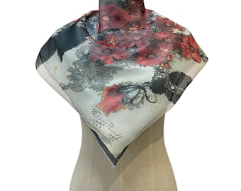 May include: A square silk scarf with a floral design in shades of red, gray, and black. The scarf is draped over a mannequin. The text "Maggy Rouff PARIS" is visible on the scarf.