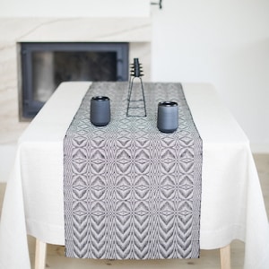 Könnte beinhalten: Eine weiße Tischdecke mit einem schwarzen und weißen geometrischen Muster-Tischläufer. Zwei schwarze Keramikbecher stehen auf dem Tischläufer.