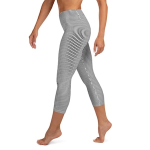 May include: Black and white striped capri leggings. The leggings feature a high waistband and a vertical stripe pattern. The capri length ends just below the knees. The leggings are made of a stretchy material.