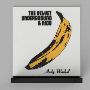 Może przedstawiać: Czarno-białe zdjęcie żółtego banana z tekstem "THE VELVET UNDERGROUND & NICO" i "Andy Warhol" wydrukowanym pod bananem.