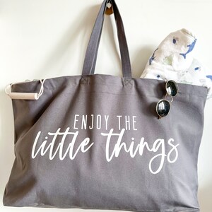 Perfect beach bag, travel companion and mothers best friend. Oversized tote in a thick durable grey canvas which says “Enjoy the little things”. These totes come in 4 different text options, two text colors and 4 tote color options.